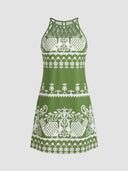 Amelia Halter Neck Mini Summer Dress in Green, white geometric and bird-motif print on green ground with crisscross braided halter neckline, front view.