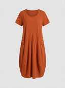 Amelia V-neck cap sleeve midi dress in rust orange-red, relaxed A-line with front patch pockets, front view on white background.