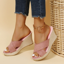 Mauve cross-strap wedge mule sandals with woven jute espadrille platform, worn with gold ankle chain, angled front view.