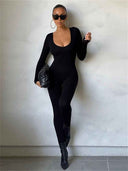 Black seamless ribbed unitard jumpsuit with scoop neck, full-body view on a light background.