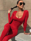 Red ribbed unitard jumpsuit with scoop neck, angled view on concrete steps.