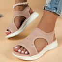 Dusty pink knit slip-on flatform sandals with open toe and curved cut-out upper, worn with denim jeans, angled front view.