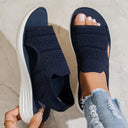 Navy blue knit slip-on flatform sandals with open toe and white platform sole, overhead angled view on marble surface.