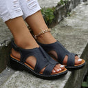 Black cushioned wedge sandals with tan arch-support footbed and contrast stitching, worn angled side view.