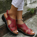 Red cushioned wedge sandals with open-toe cutout design and gold ankle chain detail, angled side view.