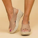 Beige espadrille platform wedge sandals with wide crossover straps and rope-wrapped jute sole, angled front view.