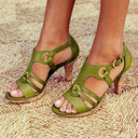 Olive green leather high heel sandals with adjustable straps and gold buckle details, front view.