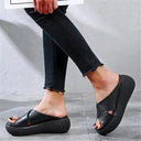 Black cross-strap platform slip-on sandals with padded flatform sole, angled side view.