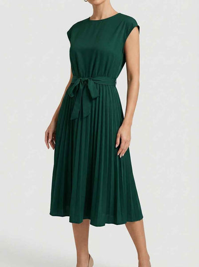 Dark green Ciara Pleated Cap Sleeve Midi Dress with self-tie bow belt, angled front view showing fully pleated A-line midi skirt, round neckline, and structured cap sleeves.