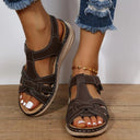 Brown low wedge sandals with woven straps, white contrast stitching and cushioned wedge sole, angled front view on feet.