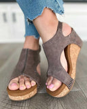 Taupe canvas platform wedge sandals with cork sole and cut-out upper, worn with distressed blue jeans, angled front view.