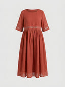 Red maxi dress with white daisy floral embroidery trim at waist and sleeves, front view on white background.