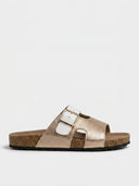 Champagne gold adjustable leather flat sandal with white buckle strap and cork footbed, side view.