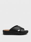 Black cross-strap wedge mule sandals with espadrille trim and lug sole, angled side view on white background.