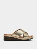Gold metallic cross-strap wedge mule sandal with espadrille rope-trim wedge and dark lug sole, side view.
