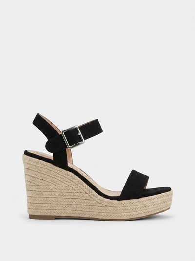 Black espadrille wedge sandal with wide forefoot strap and adjustable buckle ankle strap, side view against white background.