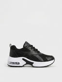 Cushioned women's trainer in Black — black mesh and synthetic leather upper with white chunky midsole and visible air-cushion pod, side view.