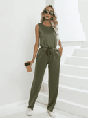 Olive green sleeveless jumpsuit with drawstring waist, front view on white stairs.
