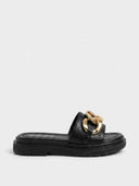 Black platform slide sandal with oversized gold curb-chain strap detail and chunky lug sole, side view.
