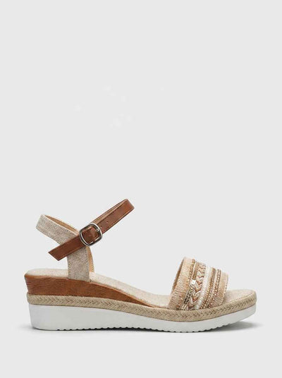 Beige espadrille wedge sandal with geometric beaded embroidered forefoot strap and tan brown ankle buckle strap, side view on white background.