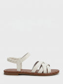 White flat strappy sandals with crisscross vamp straps and ruched elasticated ankle strap, side view on white background.