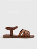 Flat strappy sandals in tan brown with crisscross vamp straps and ruched elasticated ankle strap, side view on white background.