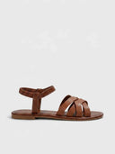 Tan brown flat sandal with woven crisscross front straps and ruched elastic ankle strap, side profile view on white background.