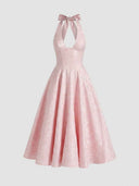 Pink halterneck mini dress with bow at back and floral jacquard pattern, front view.