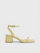 Yellow strappy sandals with square toe, adjustable silver-buckle ankle strap, and low block heel, side view on white background.