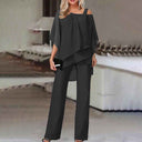 Black cold-shoulder chiffon jumpsuit with flowy long legs, front view on a blurred background.