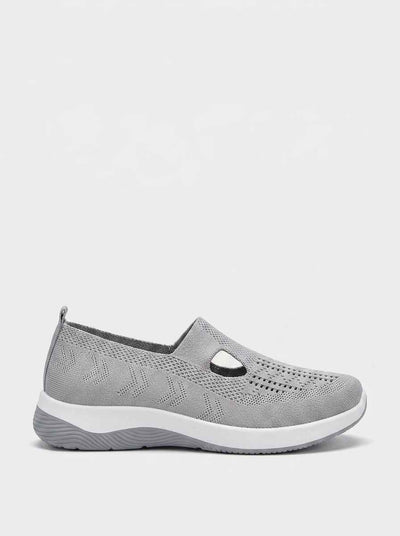Grey slip-on knit trainers with T-bar cutout strap detail and cushioned white midsole — front view on white background.