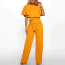 Mustard yellow wide-leg jumpsuit with short sleeves and waist tie, front view.