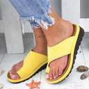 Yellow platform wedge thong sandal with wide forefoot strap, chunky treaded sole and cork-look midsole, angled front view on white background.