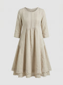 Beige linen mini dress with pleated bodice, scalloped neckline, and tiered frayed hem, front view.
