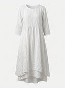 White linen mini dress with 3/4 sleeves, round neck, and tiered skirt, front view.