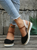 Black closed-toe espadrille wedge sandals with tan leather ankle strap and jute-wrapped platform sole, worn with distressed jeans, angled front view.