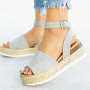 Beige espadrille flatform sandal with ankle buckle strap and woven jute platform sole, angled side view on foot.