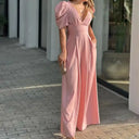 Pink jumpsuit with puffed sleeves, V-neck, and wide legs, front view.