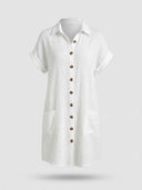 White textured shirt dress with short cuffed sleeves, brown buttons, and two pockets, front view.