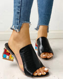 Black crocodile-texture open-toe mule sandals with multicolor jewel-encrusted block heel, angled front view.