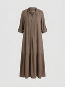 Brown tiered maxi dress with V-neck, rolled sleeves, and gold necklace, front view on gray background.