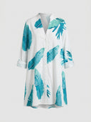 White mini sundress with blue leaf print, V-neck, and rolled sleeves, front view.