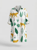 White mini sundress with leopard and green leaf print, rolled sleeves, front view.