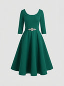 Green A-line midi dress with 3/4 sleeves and a jeweled belt, front view on a white background.