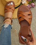 White open-toe flat sandals with criss-cross multi-strap upper and contrast-stitched tan footbed, overhead on-feet view with denim jeans.