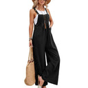 Black flared jumpsuit with button straps worn over a white tank top, front view.