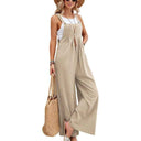 Beige flared jumpsuit with button straps and pockets, worn over a white tank top, front view.