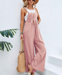 Pink flared jumpsuit with buttons, worn over a white tank top, angled view.