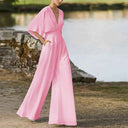 Pink dolman sleeve knit jumpsuit with V-neck, front view, outdoors by water.