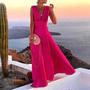 Fuchsia deep V-neck maxi dress with flowing skirt, angled view on cliffside with ocean background.